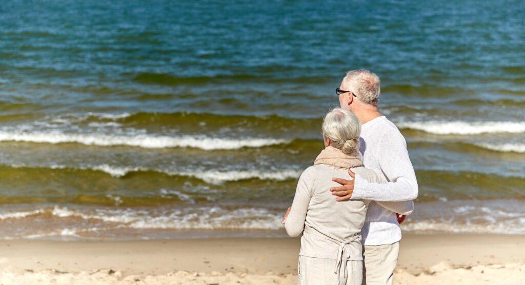 happy senior couple hugging on summer beach